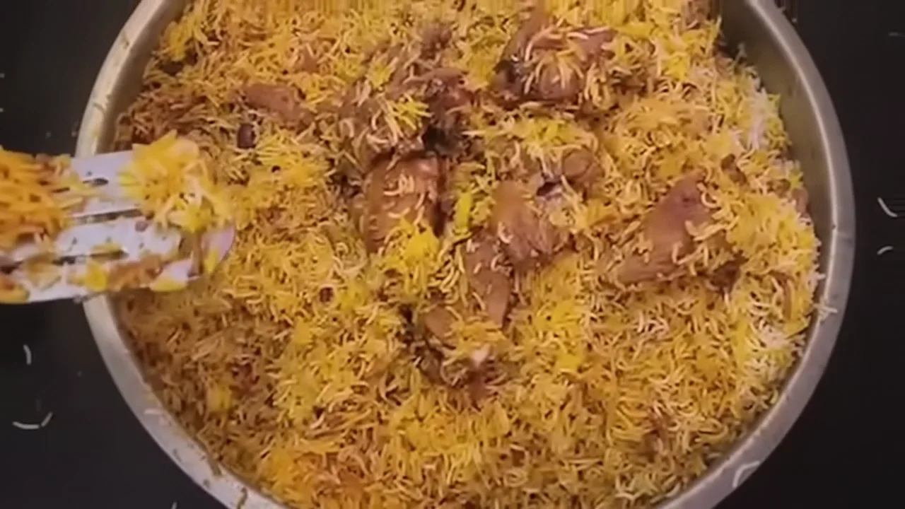 Biryani being stirred in a cooking pot